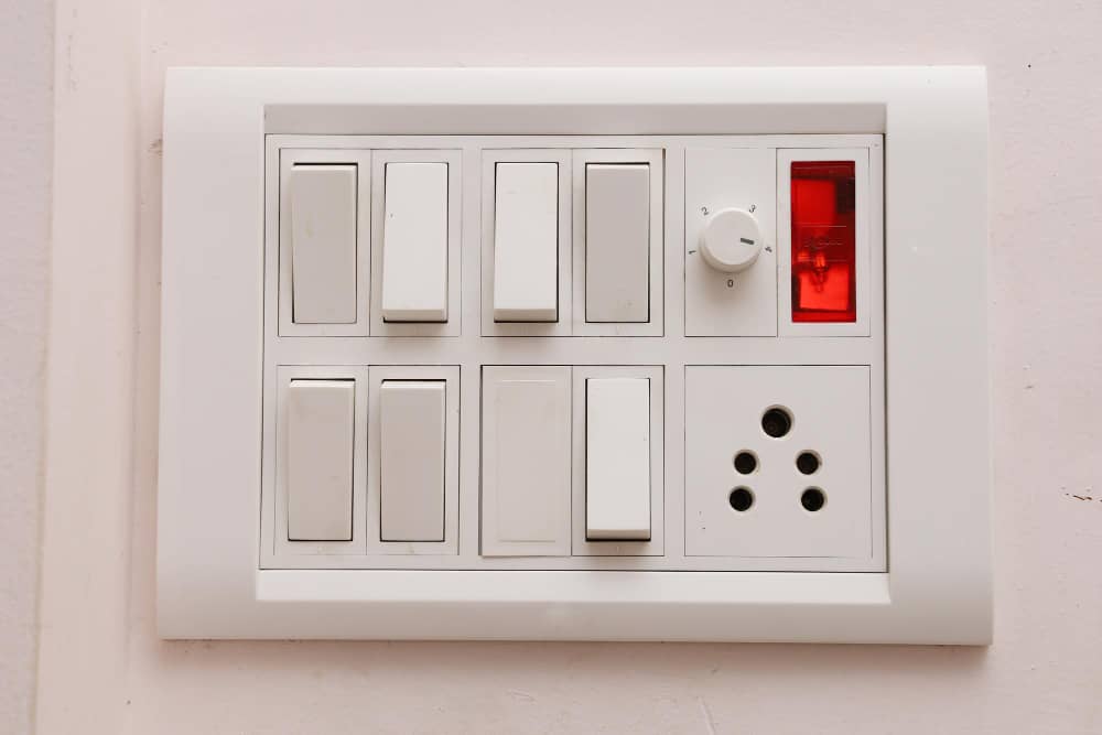 A modern electrical switchboard with multiple switches, a fan regulator, and a power socket, commonly used by fan regulator manufacturers in India.